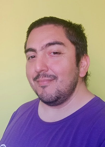 Felix Pacheco, con una polera morada y un fondo de color verde claro